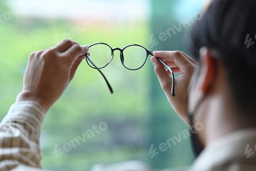 Preview: Young man is testing a new spectacles while standing in ophthalmology clinic.