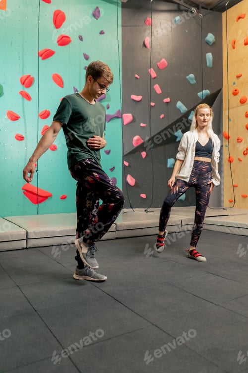 Preview: young girl at a climbing wall with a trainer doing a warm-up before rock climbing training