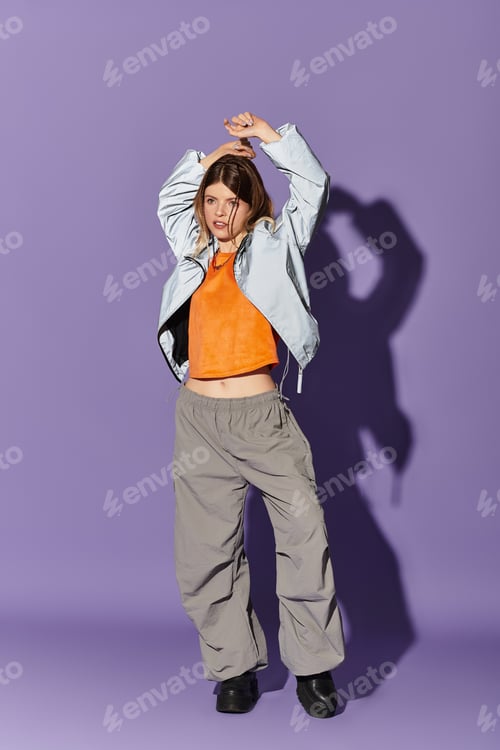 Preview: Young beautiful woman in summer attire expressing joy against a vibrant purple background