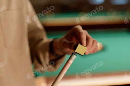 Preview: Close Up of Man Using Chalk Cube on Cue Stick Playing Pool