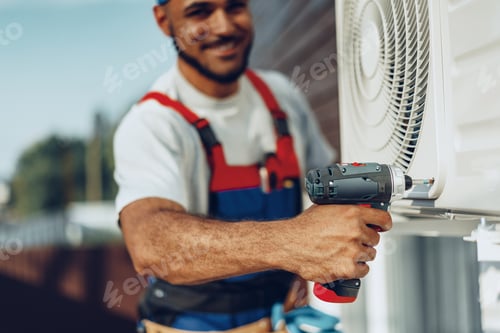 Preview: Repairman in uniform installing the outside unit of air conditioner
