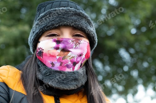 Preview: Caucasian woman wearing warm clothes and a colorful face mask - the concept of coronavirus