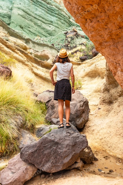Preview: A tourist woman with a hat at the Azulejos de Veneguera or Rainbow Rocks in Mogan, Gran Canaria