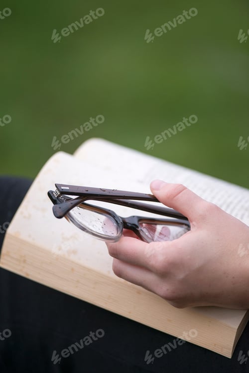 Preview: Hand with eye glasses keeping book open