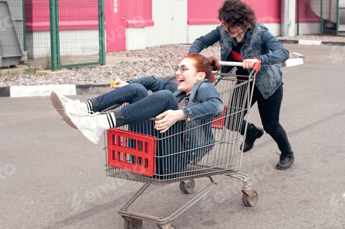 Preview: ↟ Funny happy teenage girls in denim clothes have fun and ride on the shopping cart