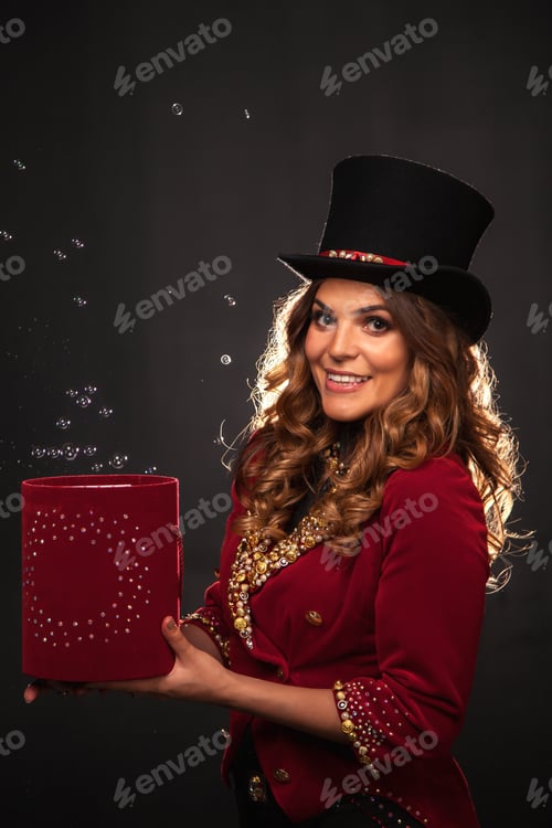 Preview: Circus actress lady in top hat holding magic red box at stage shadow, looking at camera