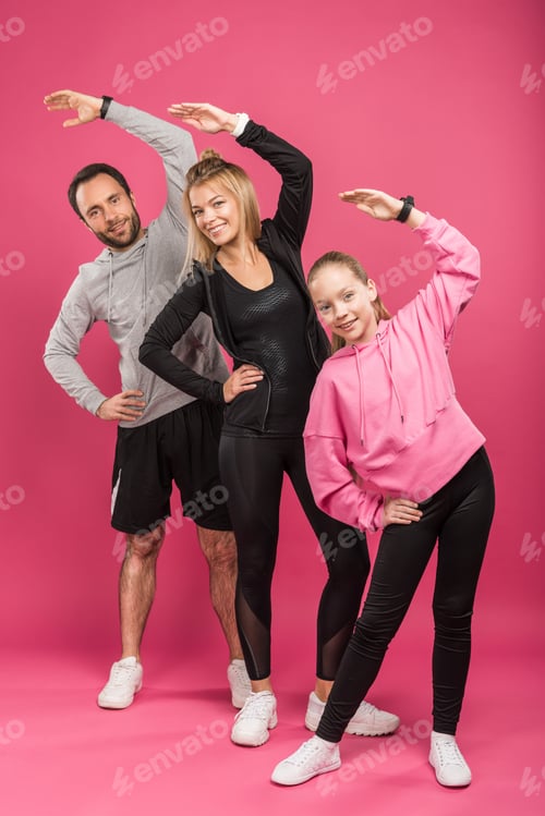 Preview: beautiful athletic family exercising on pink
