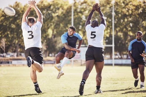 Preview: Mixed race rugby player attempting a dropkick during a rugby match outside on the field. Hispanic m