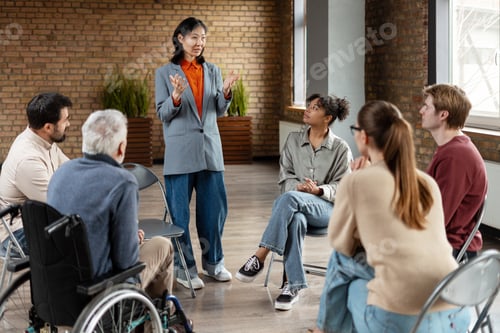 Preview: Asian businesswoman leading diverse team meeting in modern office