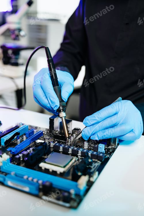 Preview: Closeup of expert soldering a green PCB board using precision tools. Ideal for electronics,