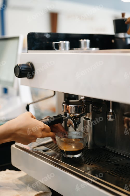 Preview: Cup and professional espresso machine pouring fresh coffee into a glass cup at cafe
