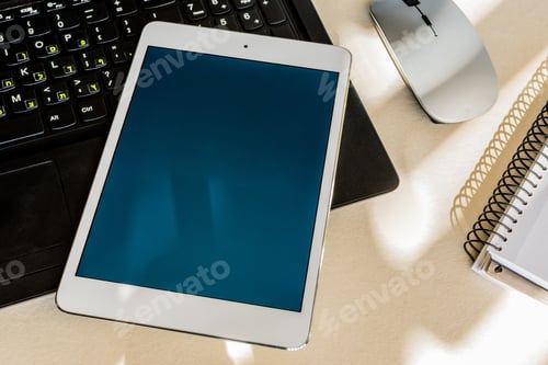 Preview: Tablet with blue screen on the keyboard of a laptop on a desk - technology and business concept