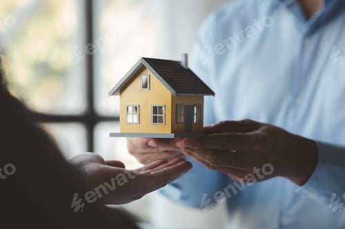 Preview: A housing salesman holds a model of a house and sends it to customers as an example.