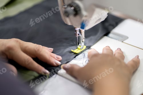 Preview: a female dressmaker working on the factory using sewing machine close up shot