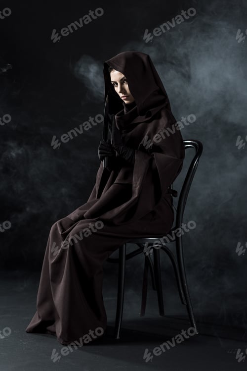 Preview: woman in death costume holding knife and sitting on chair on black