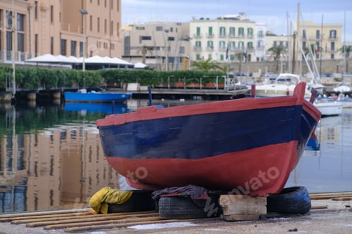 Preview: Closeup of a small wooden boat on the dock on a canal surrounded by buildings