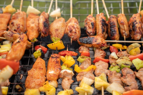 Preview: Assorted delicious grilled meat with vegetables on barbecue grill with smoke and flames.