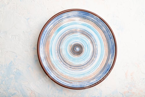 Preview: Empty blue ceramic plate on white concrete background. Top view.