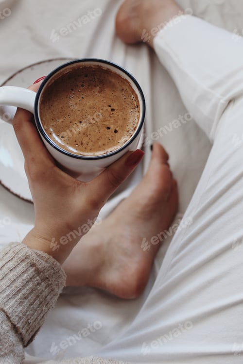 Preview: Coffee Mug Held Over White Sheets Indoors