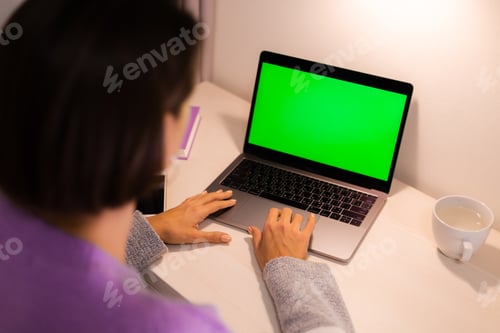 Preview: Woman at home in bedroom watching green screen on laptop on table