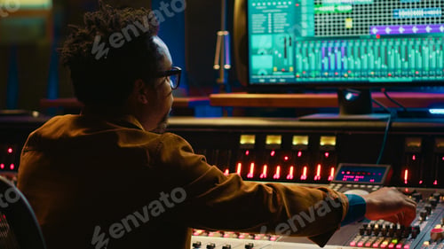 Preview: African american producer working at mixing panel in recording studio