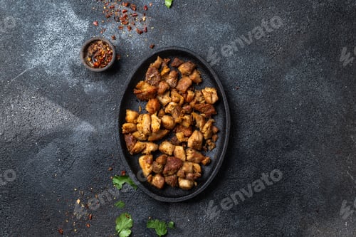 Preview: COLOMBIAN CHICHARRON. Fried pork chicharron on black plate. Top view