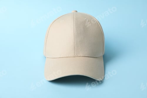 Preview: Beige baseball hat on light blue background, closeup. Mockup for design