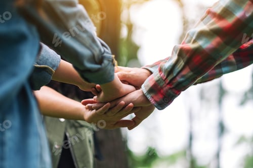 Preview: Closeup image of people putting their hands together in the outdoors