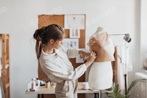 Preview: Lady in beige outfit designes clothes patterns. Brunette woman in light shirt creates stylish fashi