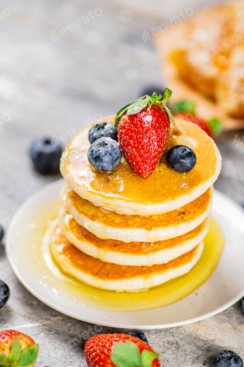 Vista previa: Pancakes with honey and berries on a plate.