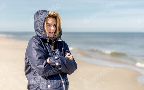 Preview: Young pretty woman at windy day walking on beach