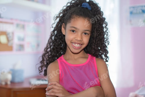 Preview: Portrait of girl with black curly hair, arms folded, looking at camera smiling