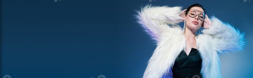Preview: brunette woman in transparent sunglasses and white furry jacket standing with hands behind head on
