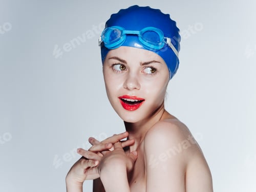 Preview: Emotional woman wearing a blue swimming cap grimaces on a light background cropped view