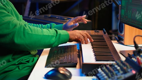 Preview: African american audio technician using piano synthesizer keys to add effects