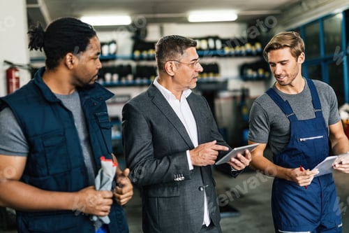 Preview: Manager using digital tablet and communicating with mechanics in auto repair shop.