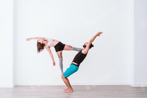 Preview: young couple Couple practicing acro yoga in white studio or gym. Healthy lifestyle