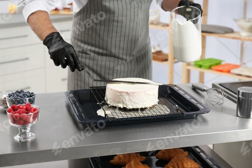 Preview: Male pastry chef preparing cake at table in kitchen, closeup
