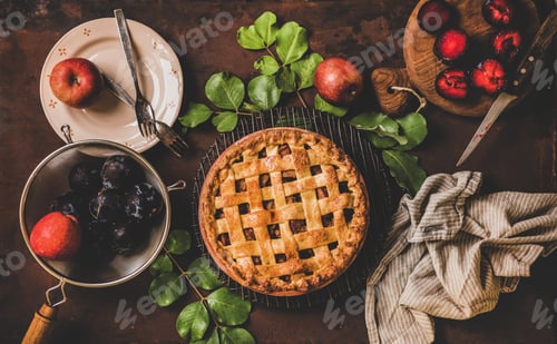 Preview: Flat-lay of whole apple and plum pie and tea setting