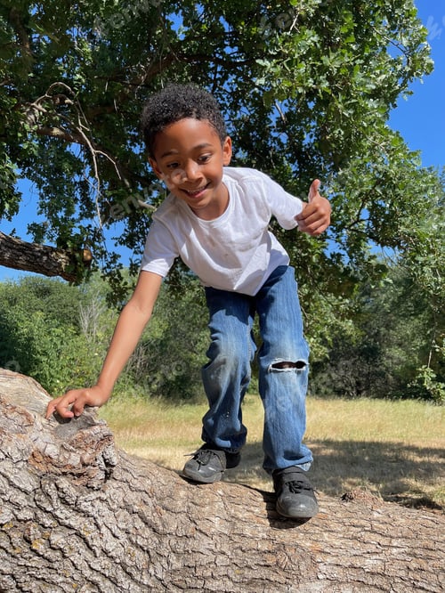 Preview: Cute cheerful African-American boy playing in a park on a sunny day