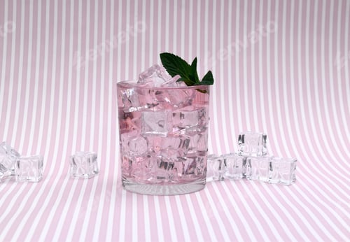 Preview: glass of clear pink drink with ice cubes on striped background