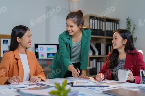 Preview: Three asian businesswomen are discussing project strategy and pointing at charts and graphs on docum