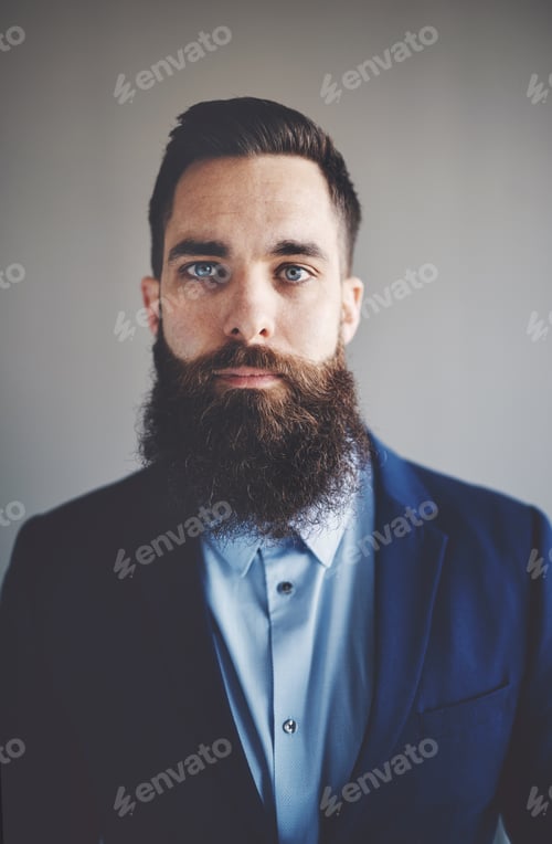 Preview: Focused young entrepreneur with a long beard wearing a blazer
