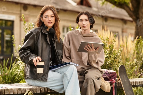 Preview: Young couple enjoying a sunny day in the park with coffee and tablets