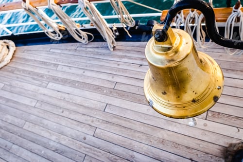 Preview: Golden bronze bell on the deck of a sailboat.