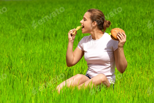 Preview: A Young Girl Eats Fast Food On A Green Field