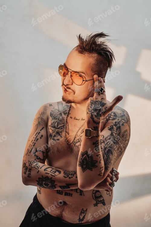 Preview: Portrait of a shirtless man with expressive haircut and tattooed body in sunglasses