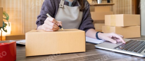 Preview: Woman is writing a list of customer on box before shipping to them, she runs an ecommerce business