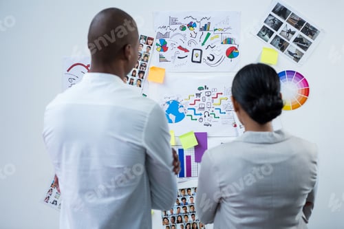 Preview: Rear view of graphic designers looking at charts and graph