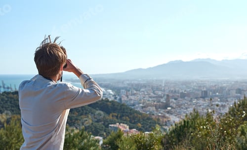 Preview: Spanish adventurous male traveler using binoculars and admiring the beautiful scenery